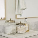 Vanity detail with glass jars and brass accents in a custom bathroom