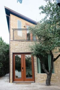 Stone home exterior with balcony and mature oak trees