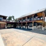 Two-story metal barndominium with limestone columns and wood garage door built by Ridge Rock Builders in the Texas Hill Country