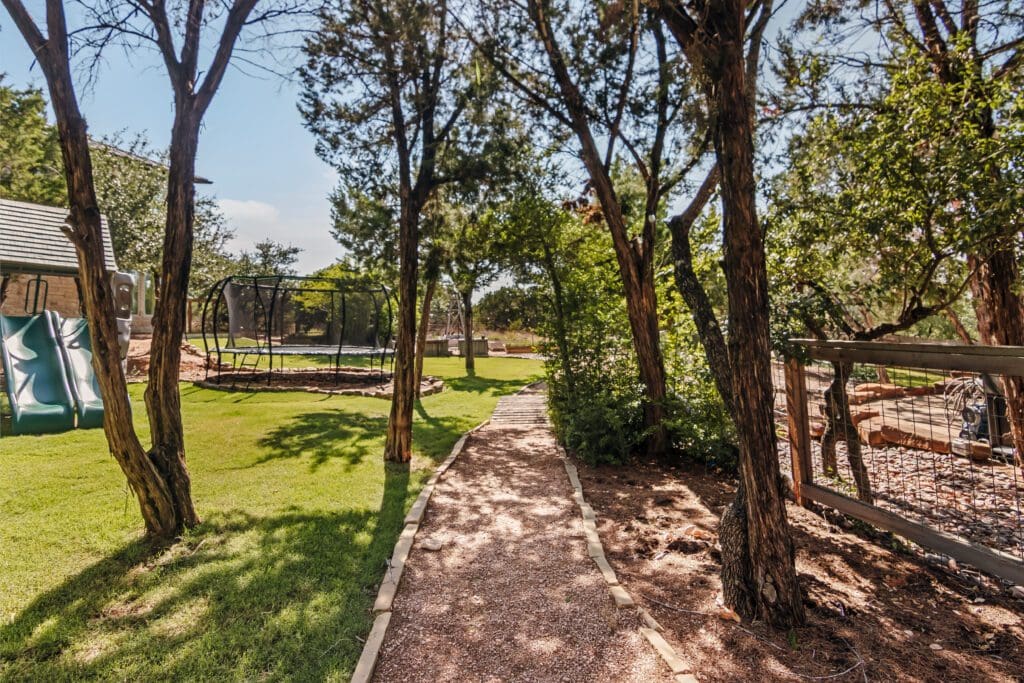 Custom home outdoor garden path and mature trees in Dripping Springs TX by Ridge Rock Builders