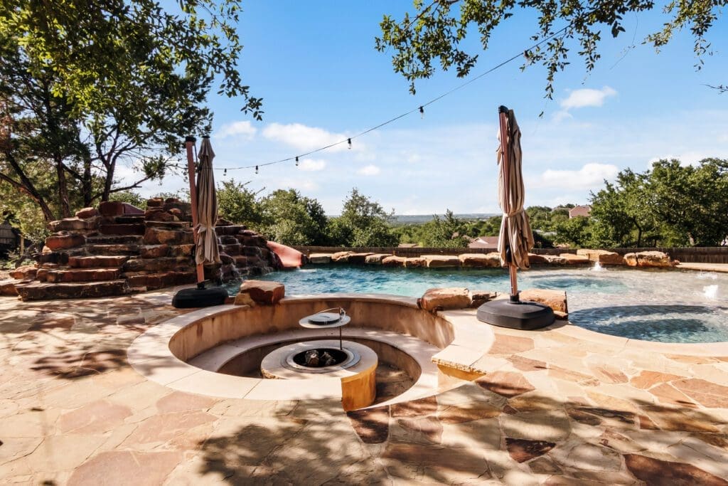Custom home outdoor patio with fire pit and stone flooring in Dripping Springs TX by Ridge Rock Builders