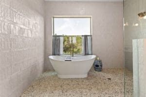Tiled bathroom with freestanding tub and garden window in a custom Hill Country home