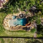 Aerial view of a custom rock pool with slide in a landscaped Dripping Springs backyard