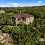 Aerial view of a custom home nestled in oak trees on Dripping Springs acreage