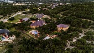 Dusk aerial of a custom home and pool on Hill Country acreage