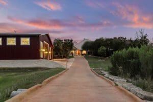 Red barn casita at dusk along a gravel drive in the Texas Hill Country