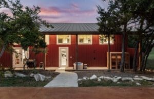 Red board-and-batten casita with metal roof built on a Hill Country property
